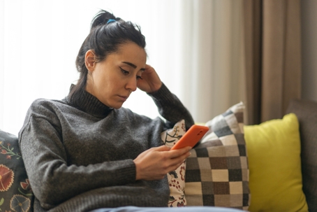 Woman looking at mobile phone screen at home.